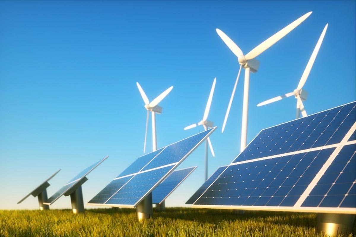 Panel surya dan turbin angin di bawah langit cerah, mewakili adopsi energi bersih di lokasi industri