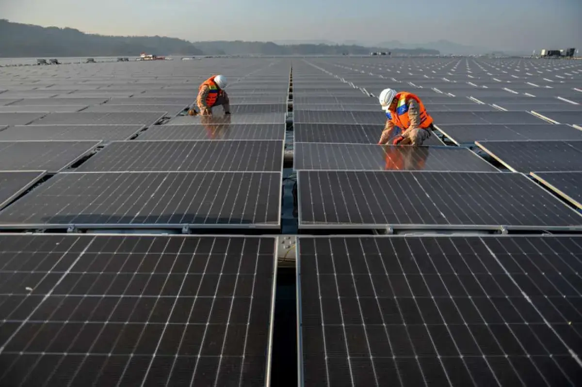 Workers installing solar panels across a large floating solar array