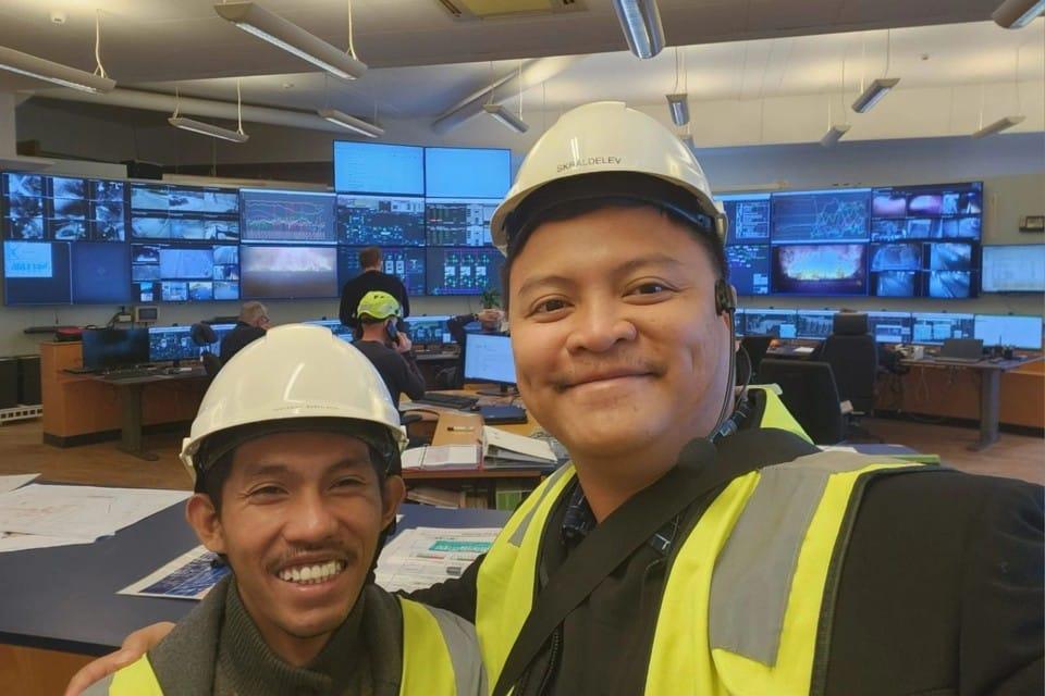 Operators in hard hats and safety vests inside a waste-to-energy plant control room