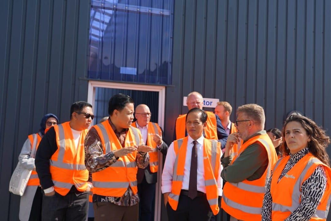Officials in high-visibility vests touring a waste processing facility