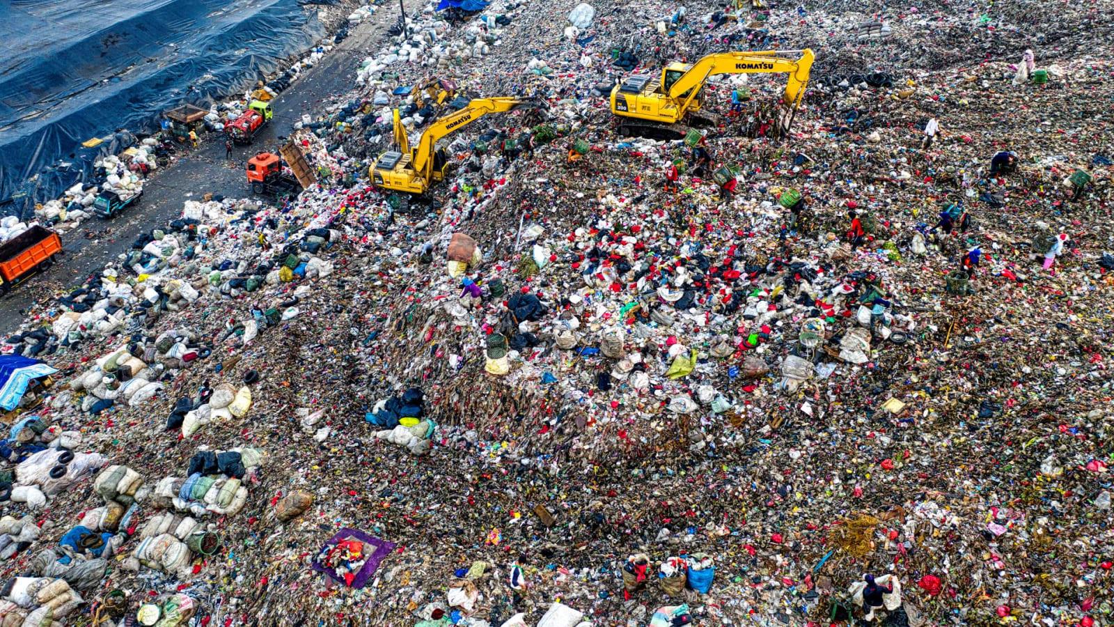 An aerial view of the Bantargebang waste processing site in Bekasi with compaction equipment working the surface of a landfill terrace