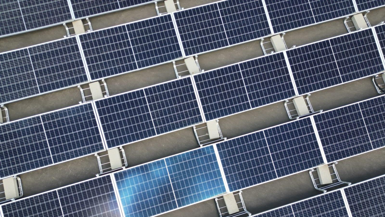 Aerial view of a large-scale solar power installation in Indonesia, panels arranged across open or floating terrain with workers or engineers inspecting equipment