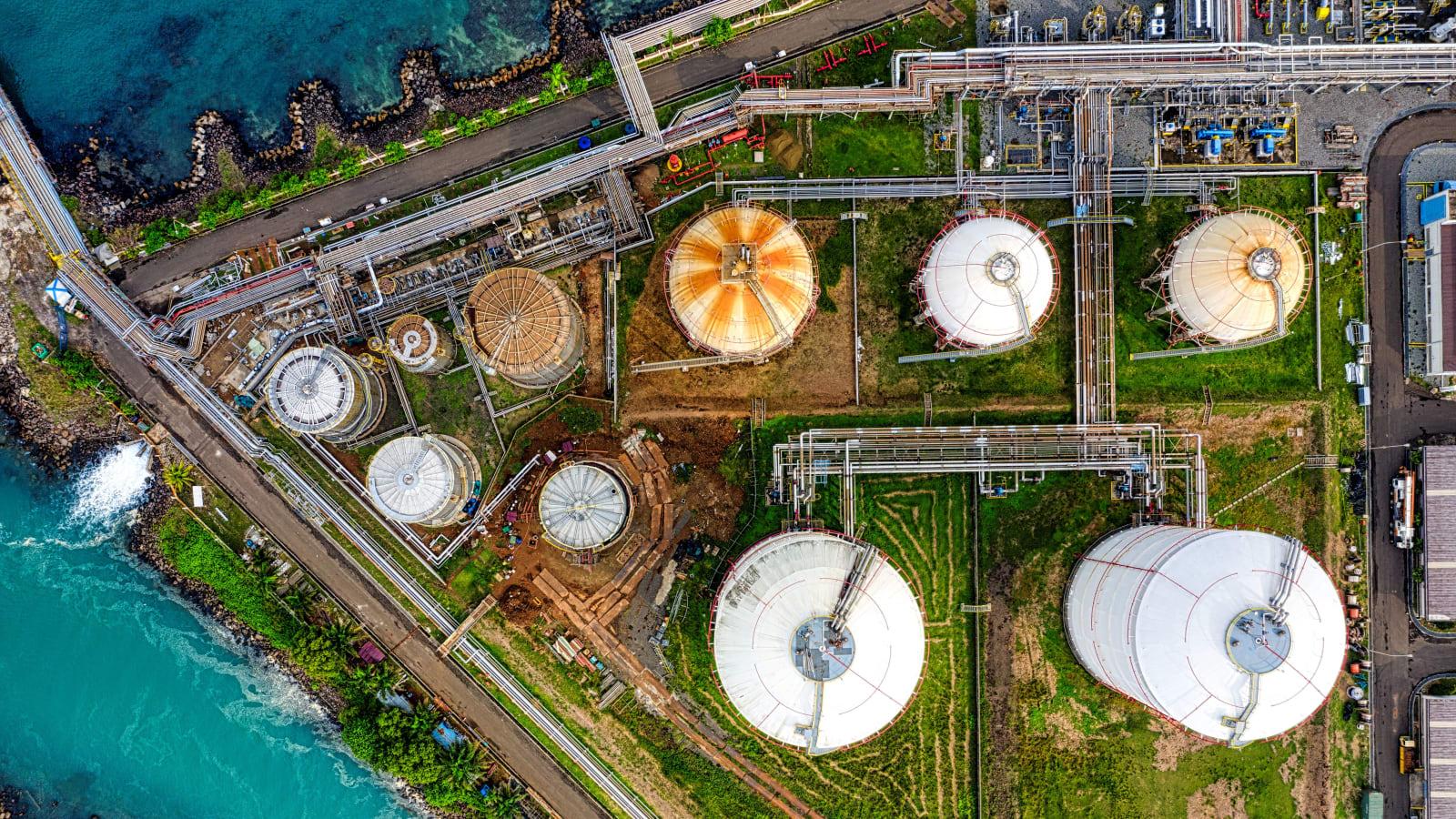 A hydrogen refueling or storage facility in Indonesia with modern industrial infrastructure, solar panels visible in the background, and a technician inspecting equipment