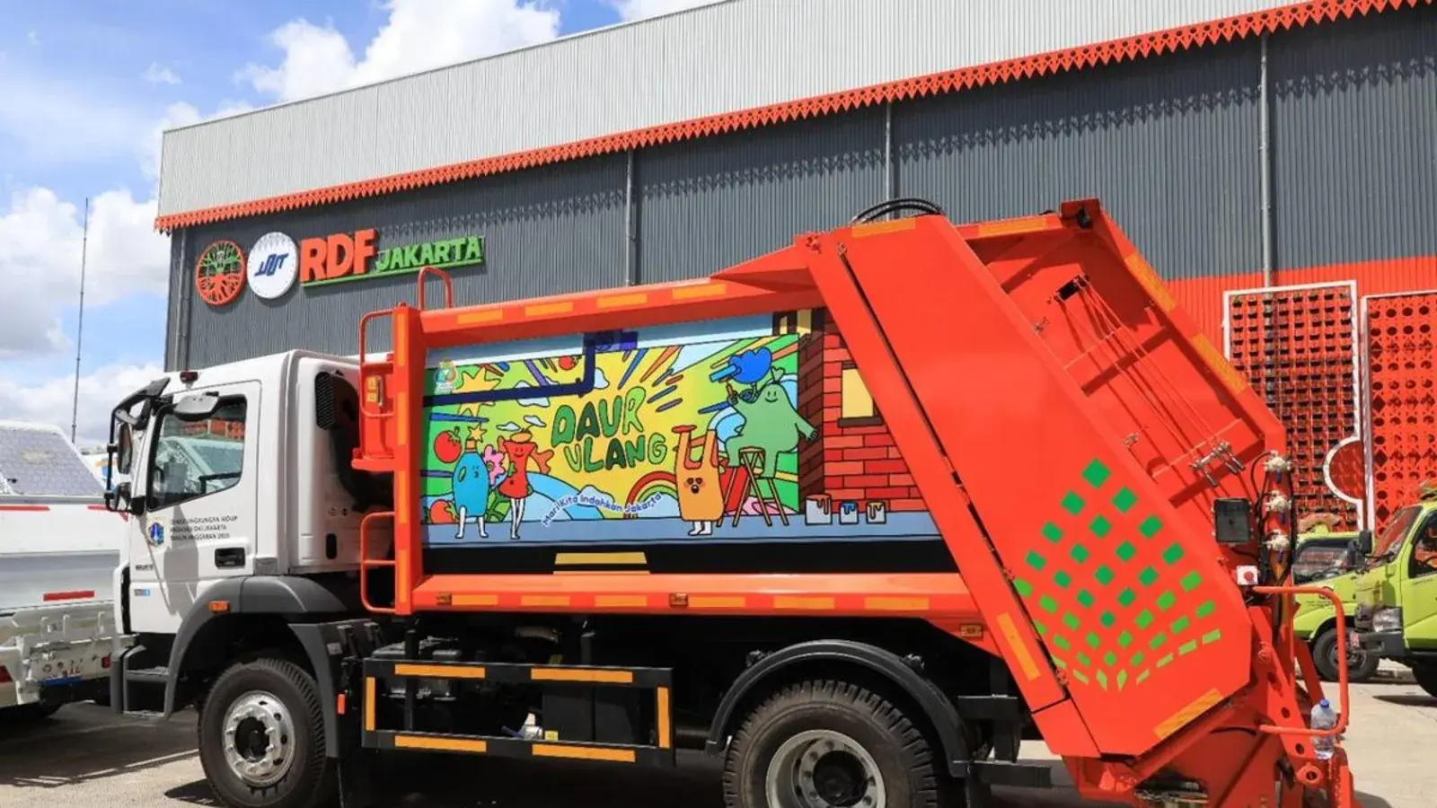 Deretan truk sampah compactor oranye yang sudah diperbarui terparkir di depo milik Pemprov DKI Jakarta, siap diserahterimakan, dengan pejabat Kota Bogor dan pejabat Jakarta memeriksa unit pemadat di bagian belakang salah satu truk