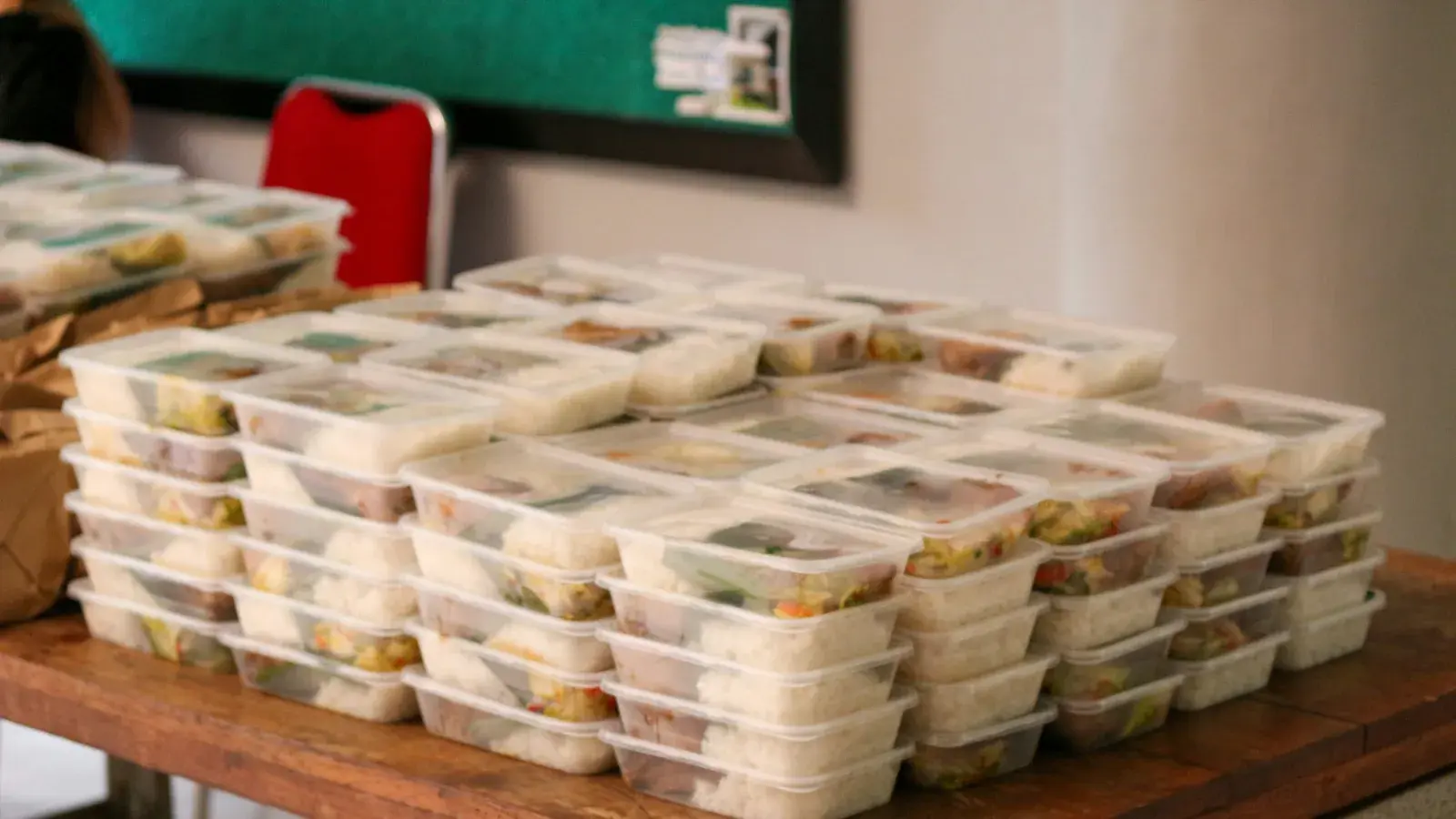 Kitchen staff at a community scale meal preparation unit separating food scraps into labelled organic and inorganic bins