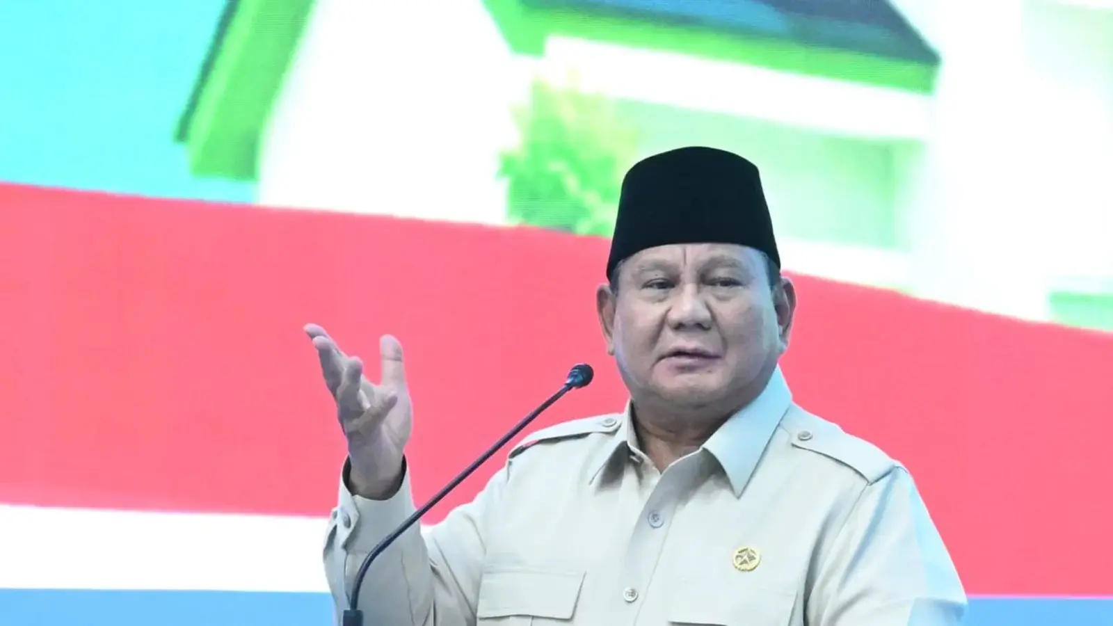 President Prabowo Subianto speaking at an outdoor public ceremony in Central Java with regional officials seated in the foreground and a newly built residential neighbourhood behind