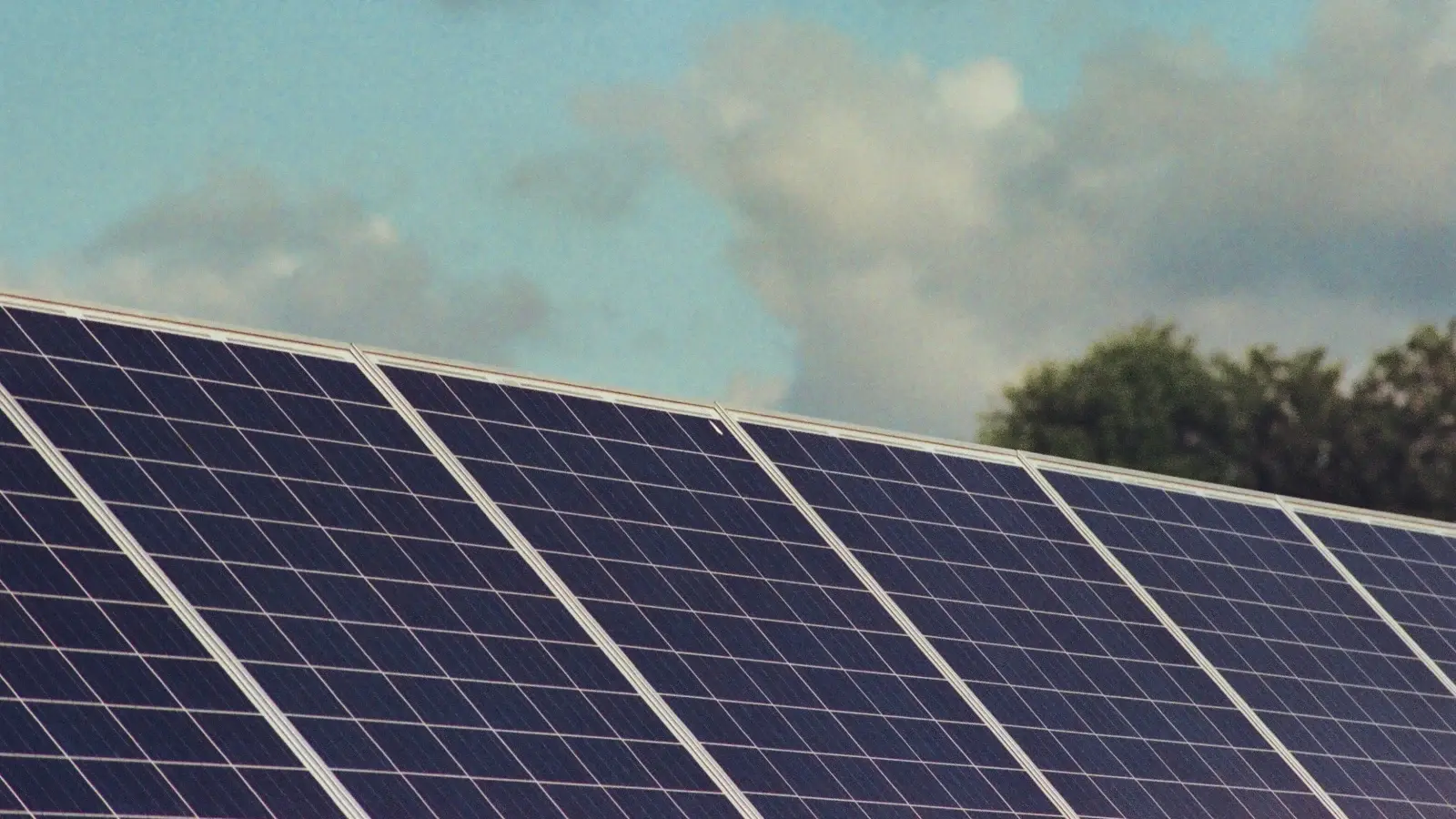 Industrial heat recovery boilers and steam piping alongside a processing plant, with a rooftop or ground mounted solar array in the background